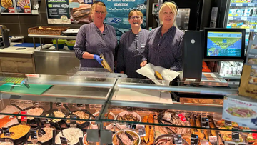 Drie medewerkers op de visafdeling laten de producten zien.